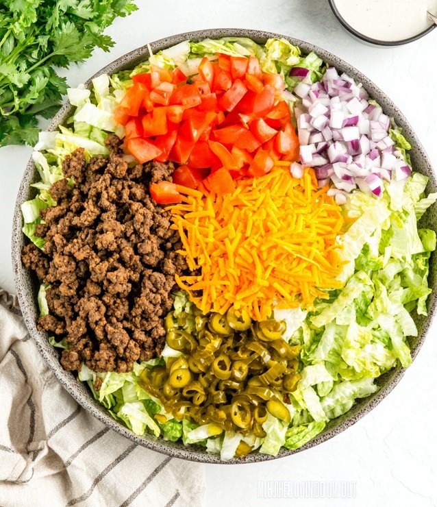 Low-Carb Big Mac Salad Ingredients - fresh lettuce, cooked beef, tomatoes, and cheese arranged in a bowl ready to mix.