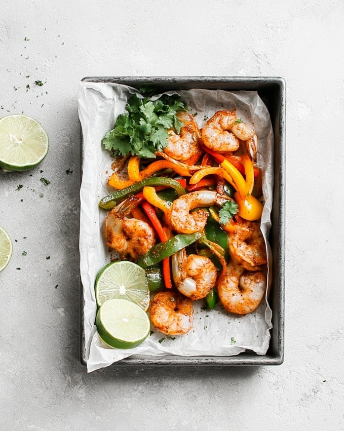Roasted shrimp and colorful peppers on the baking sheet, browned and ready to serve with lemon slices