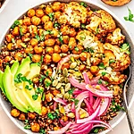 Smoky Southwest Quinoa Bowl Recipe for Busy Nights A colorful bowl filled with fluffy quinoa, golden roasted cauliflower, crispy chickpeas, sliced avocado, and pickled red onions, garnished with fresh cilantro and seeds.