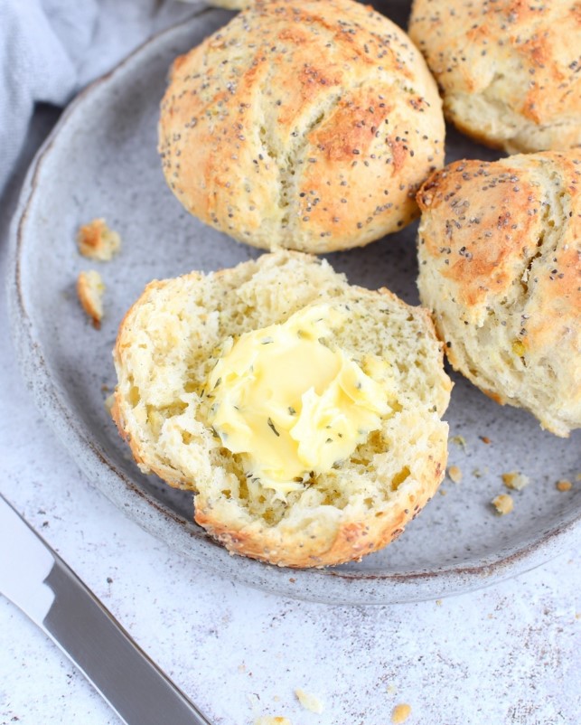 Image: A baked roll broken open to show the fluffy interior, served with melted butter.