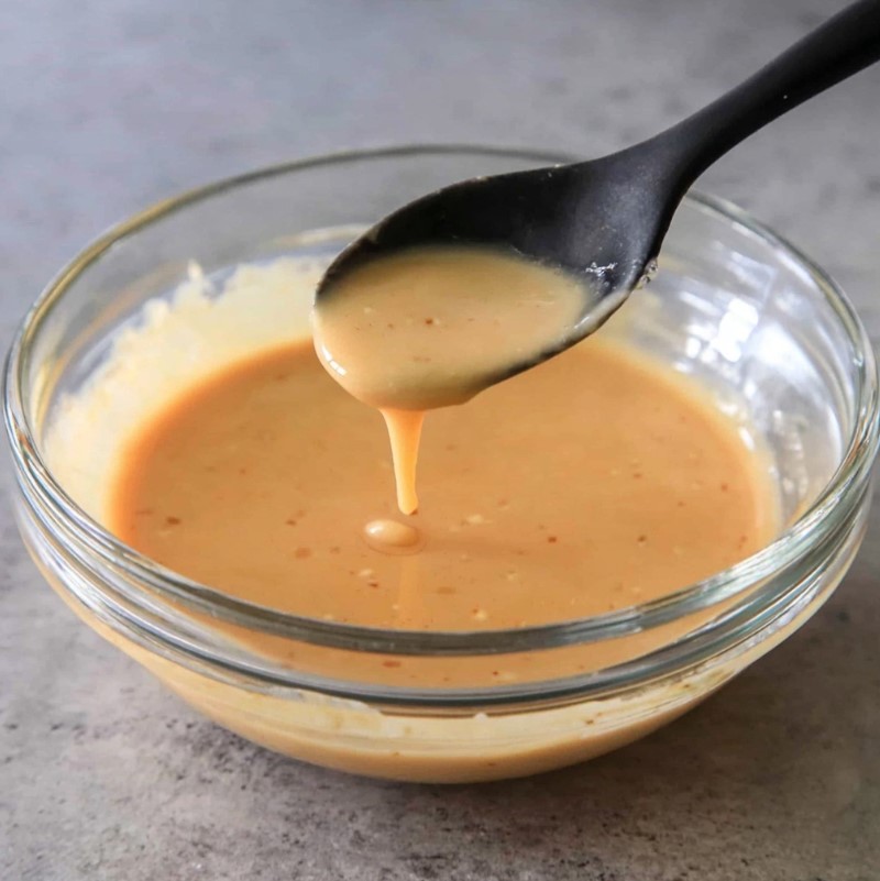 Creamy, whisked savory sauce mixture in a glass container, ready to pour.