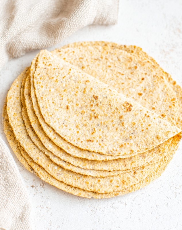A stack of warm, golden-brown keto tortillas fresh off the skillet, ready to be filled.