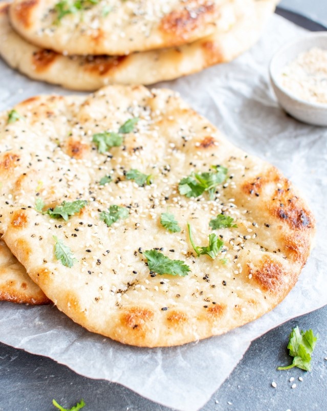 Baked naan bread, browned and seasoned (like with za'atar or sesame) ready to serve.