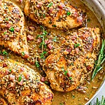 One-Skillet Honey Mustard Chicken Recipe with Bacon (Sweet, Savory & Effortless) The final stage before serving, the chicken is cooked and covered in a thick creamy mustard sauce and garnished with herbs and bacon.