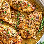 One-Skillet Honey Mustard Chicken Recipe with Bacon (Sweet, Savory & Effortless) The final stage before serving, the chicken is cooked and covered in a thick creamy mustard sauce and garnished with herbs and bacon.
