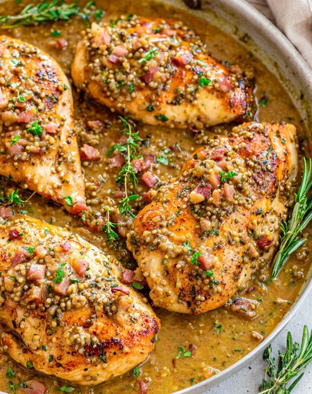 The final stage before serving, the chicken is cooked and covered in a thick creamy mustard sauce and garnished with herbs and bacon.