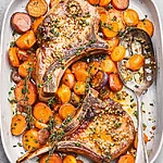 Sticky & Savory Sheet Pan Maple Mustard Pork Chops Final plated dish showing bone-in pork chops with roasted carrots, herbs, and thickened mustard sauce ready to serve