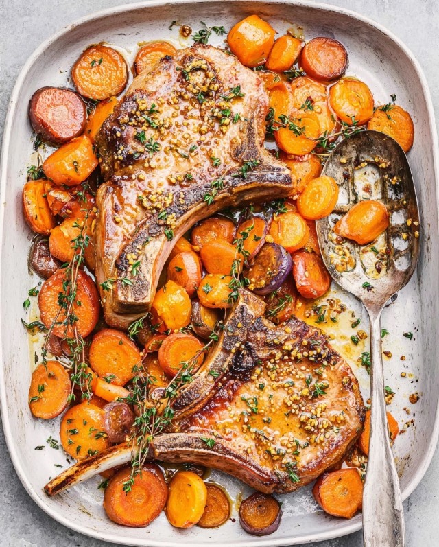 Final plated dish showing bone-in pork chops with roasted carrots, herbs, and thickened mustard sauce ready to serve