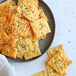 Crispy Keto Cheddar Crackers: A Savory 2-Ingredient Snack Golden baked crackers cut into squares, fresh from the oven and sprinkled with seeds.