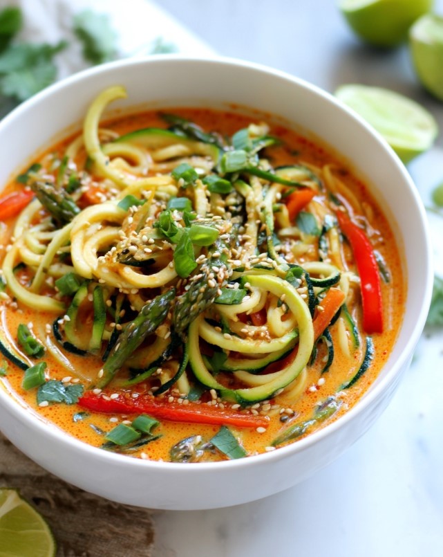 Low-Carb Thai red curry zucchini noodles - bowl of creamy orange coconut broth with zucchini noodles garnished with sesame seeds and cilantro