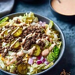 Low carb Big Mac salad in a wide bowl layered with seasoned beef, pickles, and creamy burger sauce