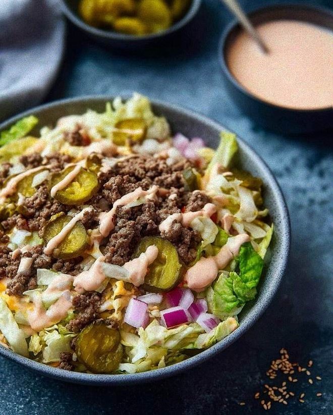 Low carb Big Mac salad in a wide bowl layered with seasoned beef, pickles, and creamy burger sauce
