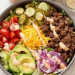 Wide bowl filled with crisp iceberg lettuce, caramelized ground beef crumbles, sharp cheddar, cherry tomatoes, and pink sauce