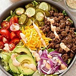 Low-Carb Cheeseburger Salad Bowl in 25 Minutes Wide bowl filled with crisp iceberg lettuce, caramelized ground beef crumbles, sharp cheddar, cherry tomatoes, and pink sauce