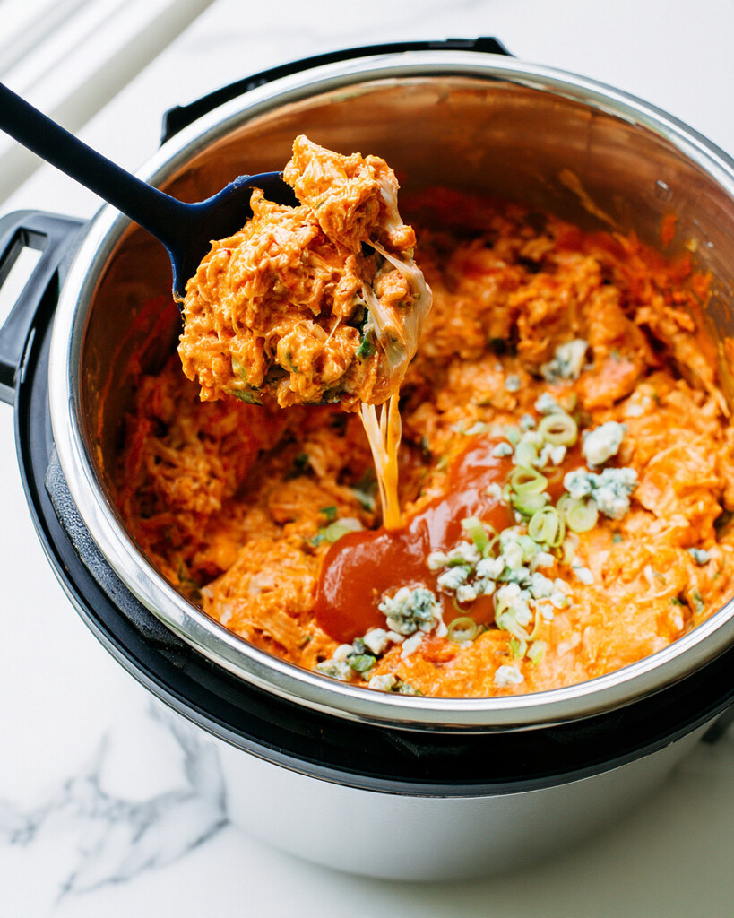 Hot buffalo chicken dip scooped straight from the pot with a visible cheese pull
