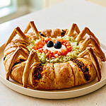 Garlic-butter spider taco ring with golden crescent dough legs and sour cream spider eyes in the center